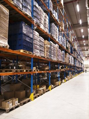 Interior of large distribution warehouse with shelves stacked with palettes and goods ready for the market.